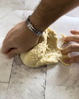 Una persona sta impastando un pezzo di pasta su un tavolo.