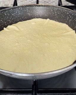 Una padella piena di tortilla sta cuocendo sul fornello.