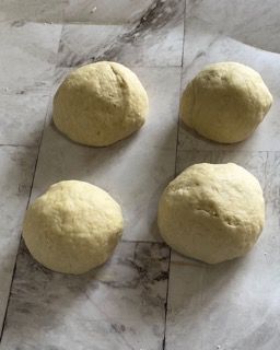 Quattro palline di pasta sono appoggiate su una superficie di marmo.