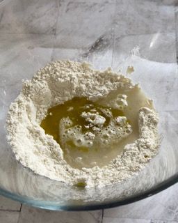 Una ciotola di vetro piena di farina e olio su un tavolo.