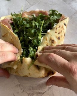 Una persona sta togliendo una tortilla da una pizza