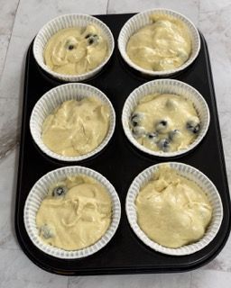 Uno stampo per muffin riempito con sei tazze di pastella e mirtilli