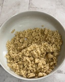 Una ciotola bianca piena di briciole su un tavolo.