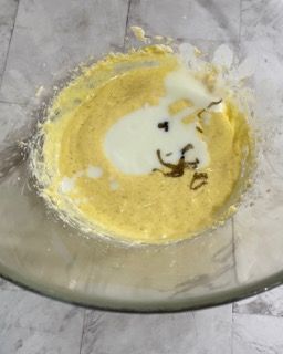 Una ciotola di vetro piena di un liquido giallo e di un liquido bianco.
