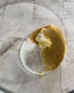 Un pezzo di burro è appoggiato su una ciotola di zucchero di canna.