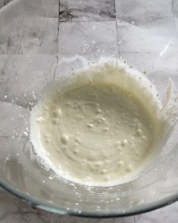 Una ciotola di vetro piena di un liquido bianco su un tavolo.