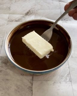 Un pezzo di burro sporge da una ciotola con una forchetta