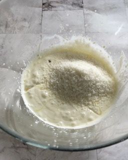 Una ciotola di vetro piena di un liquido bianco e zucchero a velo.