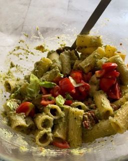 Un primo piano di un'insalata di pasta con pomodori e lattuga