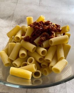 Una ciotola di vetro piena di pasta e salsa su un tavolo