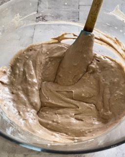 Una ciotola di glassa al cioccolato con una spatola dentro.