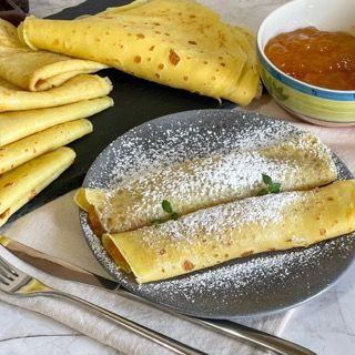 Un piatto di cibo con zucchero a velo e una ciotola di marmellata