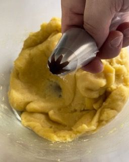 Una persona tiene un beccuccio per dolci sopra una ciotola di pasta