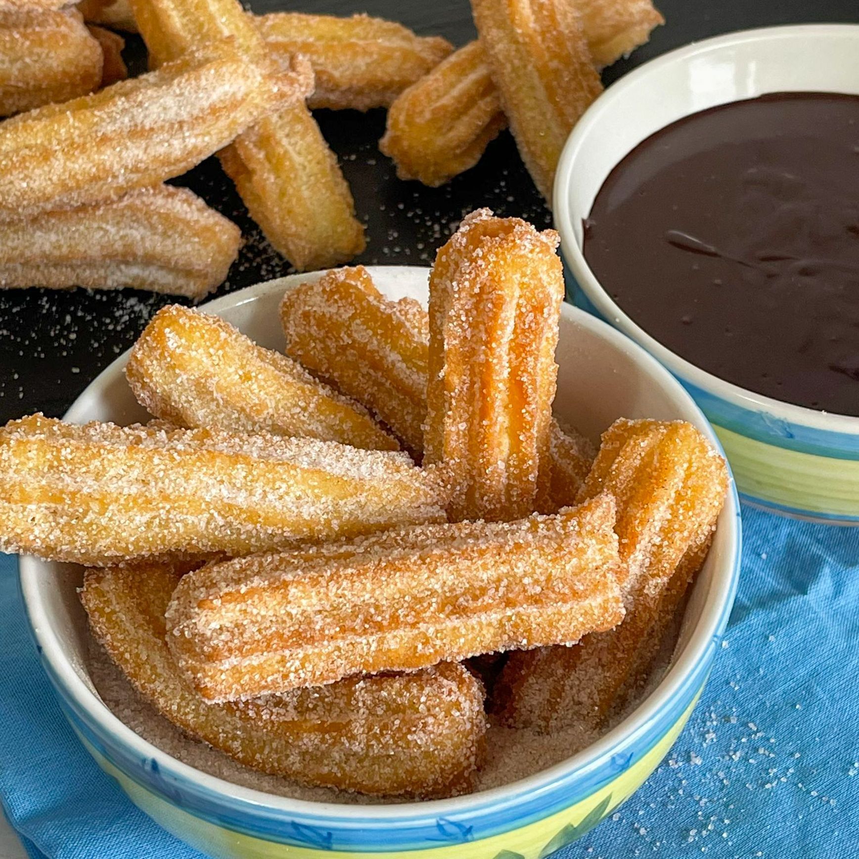 Una ciotola di churros accanto a una ciotola di salsa al cioccolato.