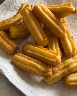 Un mucchio di churros su un tovagliolo di carta su un tavolo.