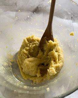 Un cucchiaio di legno è in una ciotola di impasto.