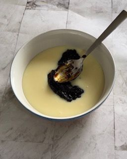 Una ciotola di yogurt con un cucchiaio dentro.
