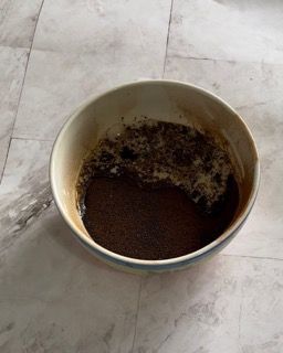 Una ciotola bianca piena di liquido marrone su un pavimento piastrellato