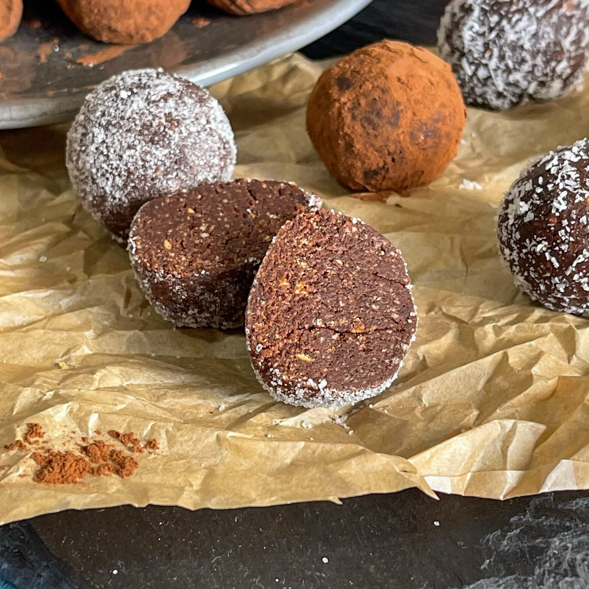 Un primo piano di un tartufo al cioccolato con un morso preso su un tavolo.