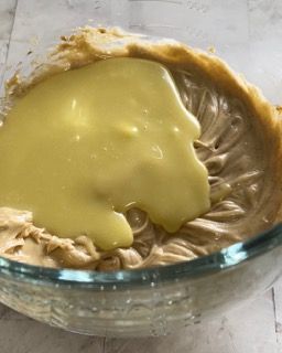 Una ciotola di vetro piena di panna montata e salsa gialla.