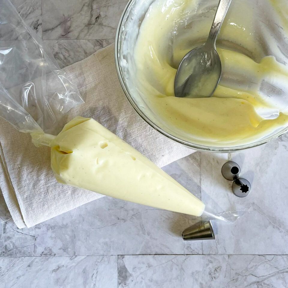 Una busta di glassa accanto a una ciotola di glassa con un cucchiaio dentro