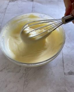 Una persona sta sbattendo una ciotola di yogurt con una frusta.