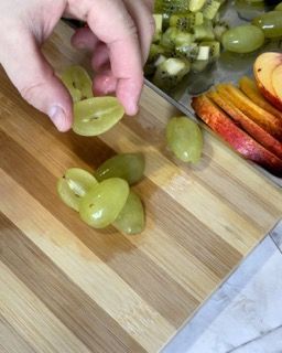 Una persona sta tagliando l'uva su un tagliere di legno