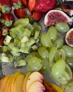 Un piatto di frutta con fragole, kiwi, uva e fichi