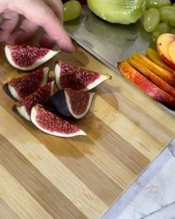 Una persona sta tagliando i fichi su un tagliere di legno