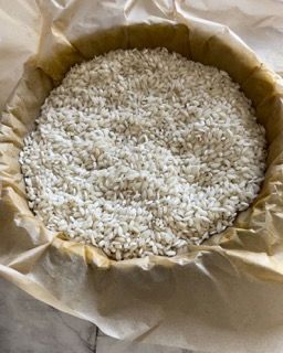 Una ciotola piena di riso bianco è appoggiata su un tavolo.