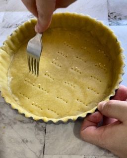 Una persona tiene una forchetta sopra una crosta di torta