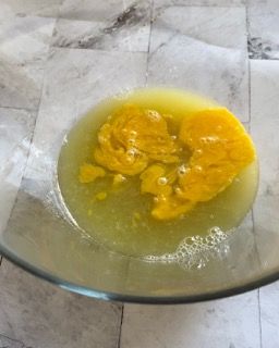 Una ciotola di vetro piena di liquido giallo su un tavolo.