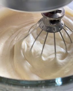 Un primo piano di un mixer con panna montata al suo interno.
