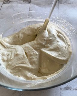 Una ciotola di vetro piena di panna montata con un cucchiaio dentro