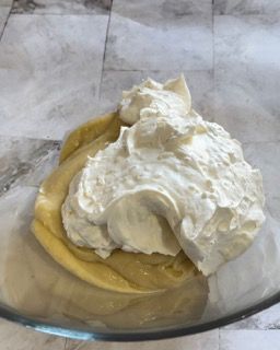 Una ciotola di vetro piena di liquido giallo e panna montata