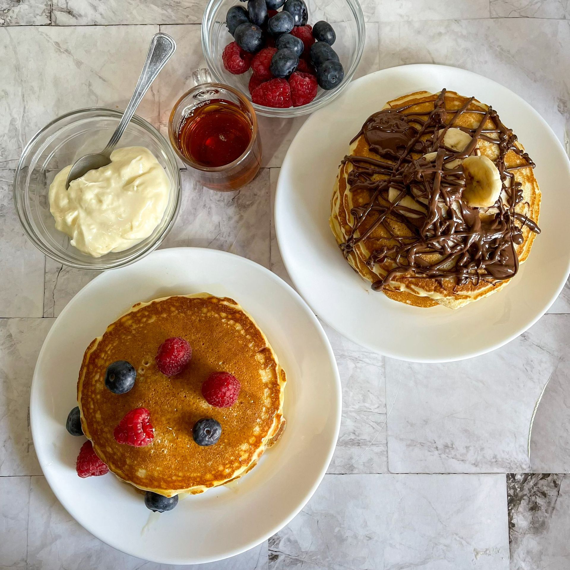 Due piatti di pancake con bacche e cioccolato sopra