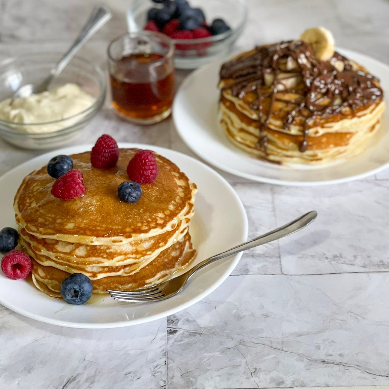 Una pila di pancake con lamponi e mirtilli sopra