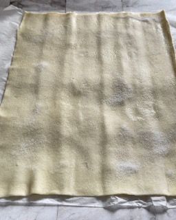 Un pezzo di pasta sfoglia è appoggiato su un foglio di carta oleata.