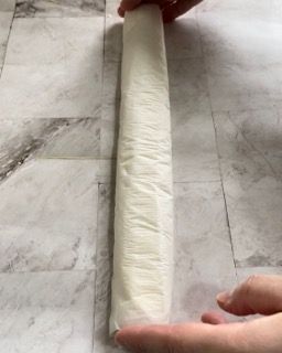 Una persona tiene in mano un lungo pezzo di carta su un tavolo.