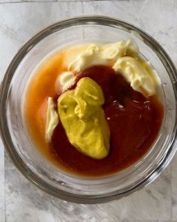Una ciotola di vetro piena di ketchup, senape e maionese