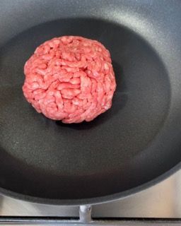 Un pezzo di carne macinata viene cucinato in una padella