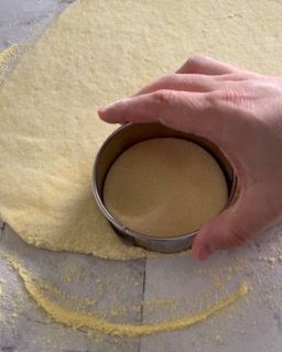 Una persona sta usando uno stampino per biscotti per tagliare un pezzo di pasta.