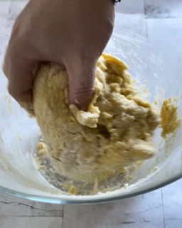 Una persona sta mescolando l'impasto in una ciotola di vetro.