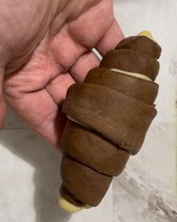 Una persona tiene in mano un croissant al cioccolato.