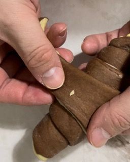 Una persona tiene in mano un croissant al cioccolato.