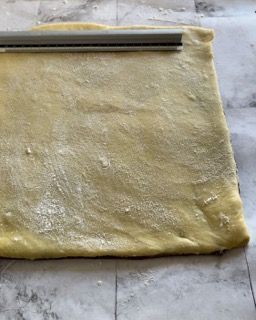 Un pezzo di pasta con un mattarello sopra.