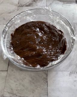 Una ciotola di vetro piena di cioccolato ricoperta di pellicola trasparente