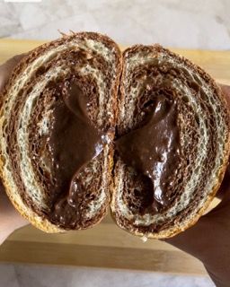 Una persona tiene in mano un pezzo di pane al cioccolato tagliato a metà