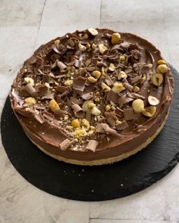 Una torta al cioccolato con sopra delle noci è su un piatto nero