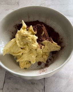 Una ciotola bianca piena di burro e cacao in polvere